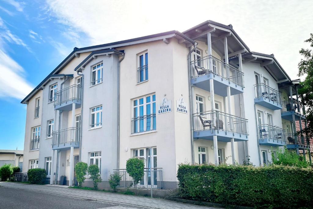 a white building with balconies on a street at Villa Karina by Rujana in Göhren