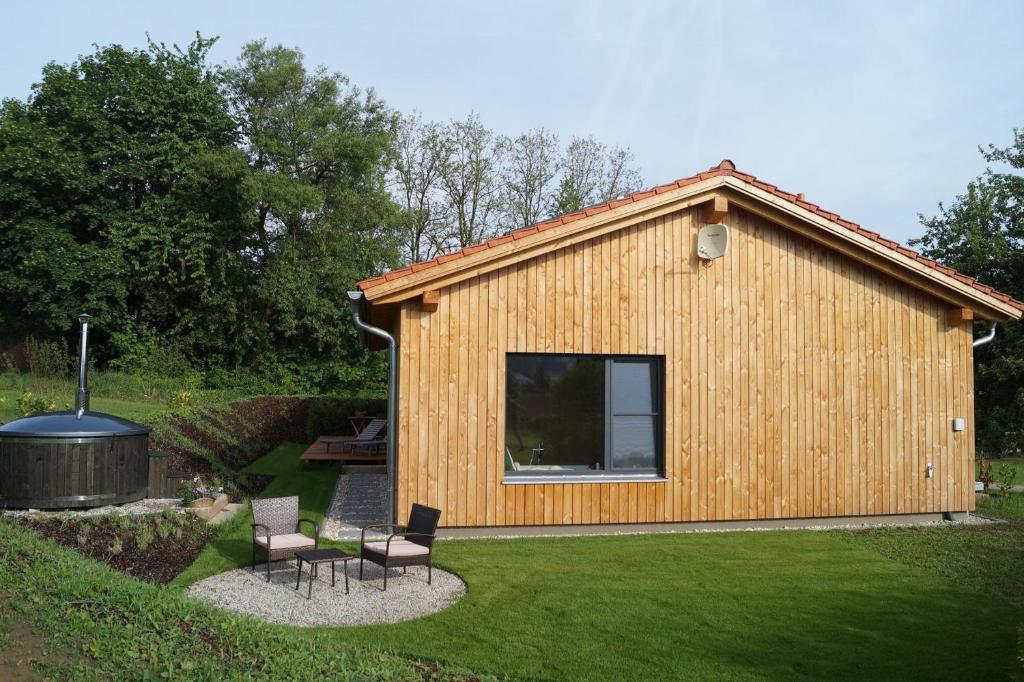 Cabaña de madera pequeña con sillas y parrilla en Waldheimat, en Miltach