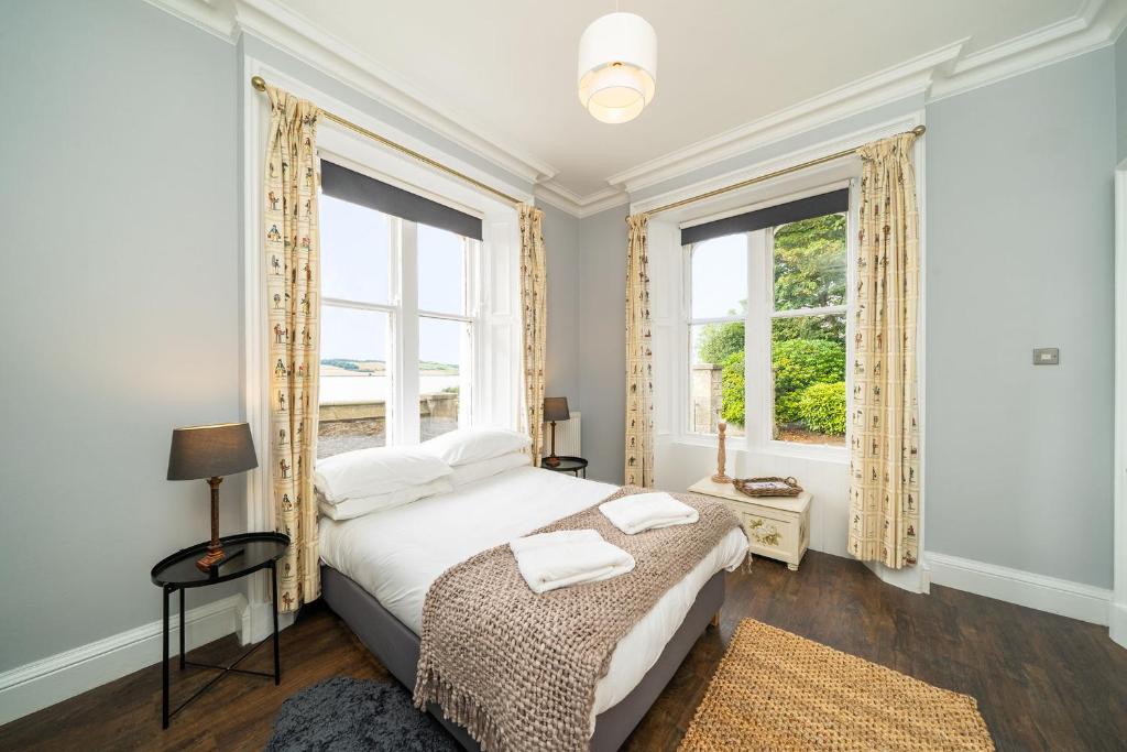 a bedroom with a bed and two windows at The Gate Lodge in Broughty Ferry
