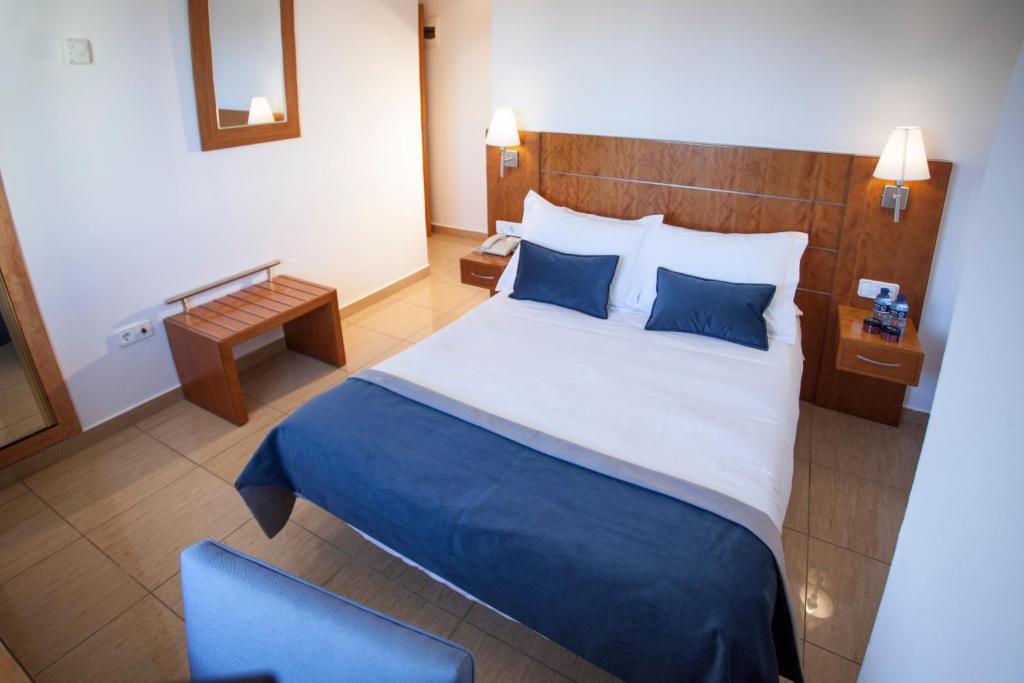 sypialnia z dużym łóżkiem i niebieskim krzesłem w obiekcie La Callejuela w mieście Villarejo de Salvanés