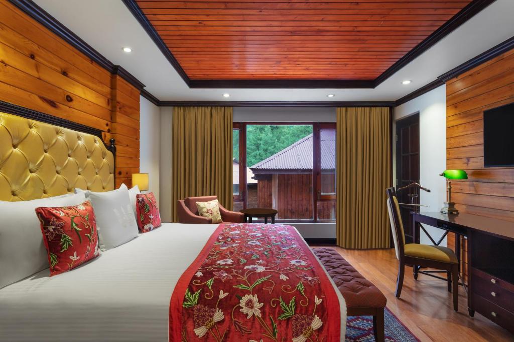 a hotel room with a bed and a desk and a television at Welcomhotel by ITC Hotels, Pine N Peak, Pahalgam in Pahalgām