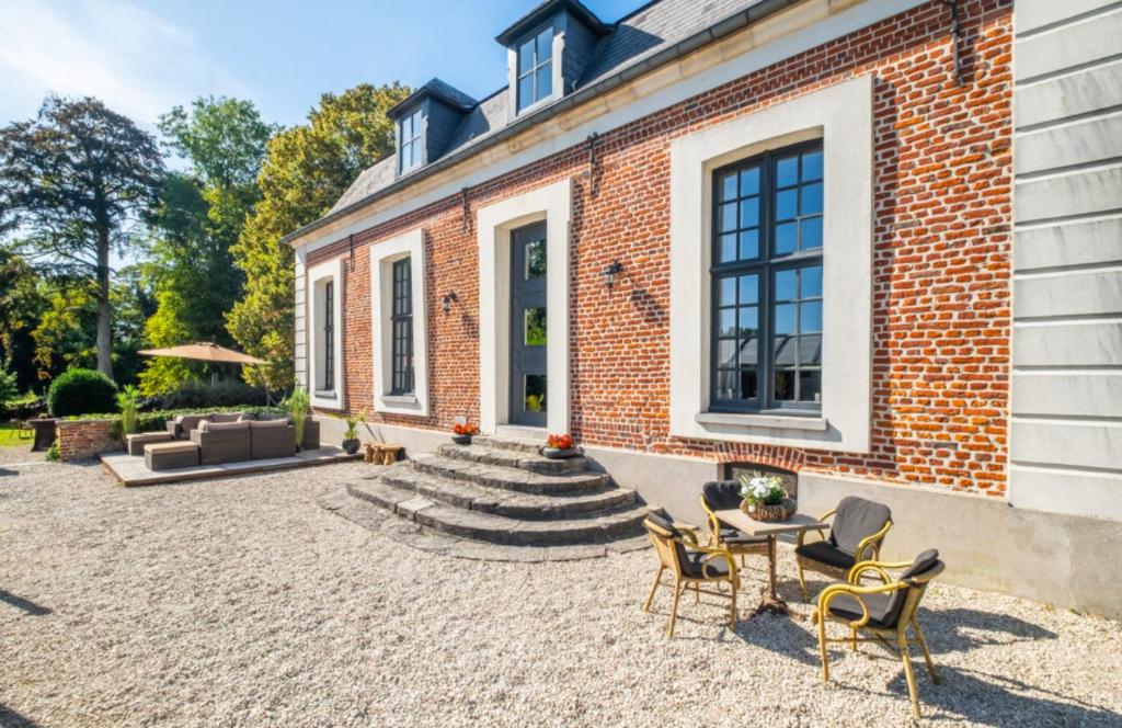 a brick house with a patio with chairs and a table at La Ragotière in Froyennes