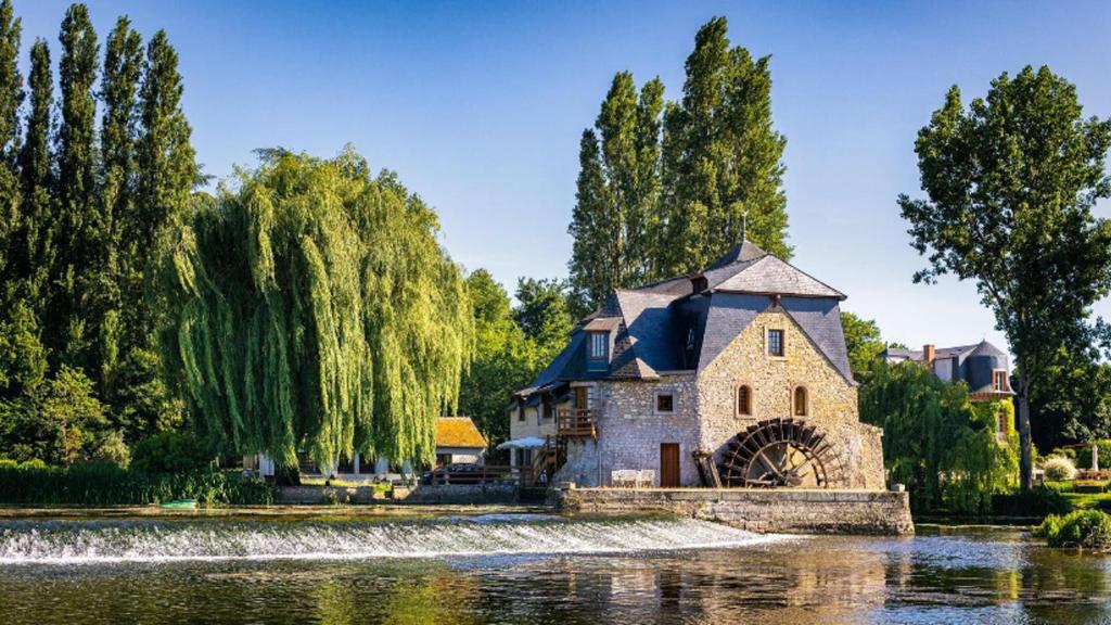 a house in the middle of a lake with a fountain at Moulin d'Ignières in Parcé-sur-Sarthe