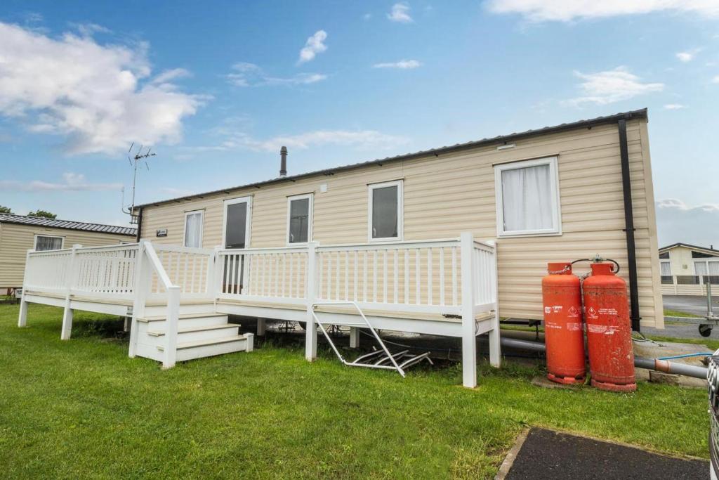 a mobile home with a deck and two fire hydrants at Lovely Caravan With Decking At Seawick Holiday Park In Essex Ref 27471sw in Clacton-on-Sea