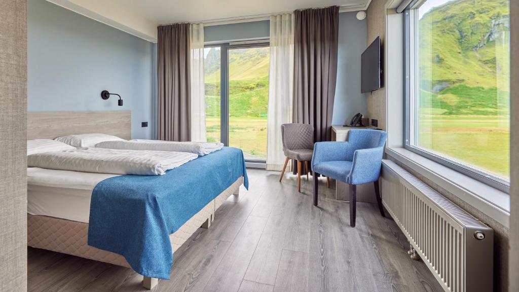 a hotel room with two beds and a desk and a window at Hótel Kría in Vík