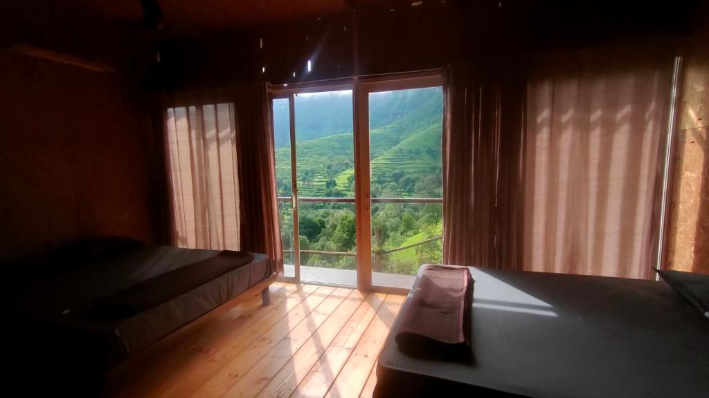 a room with a large window with a view at The Tribe Agrotourism, Wai mahabaleshwar in Panchgani