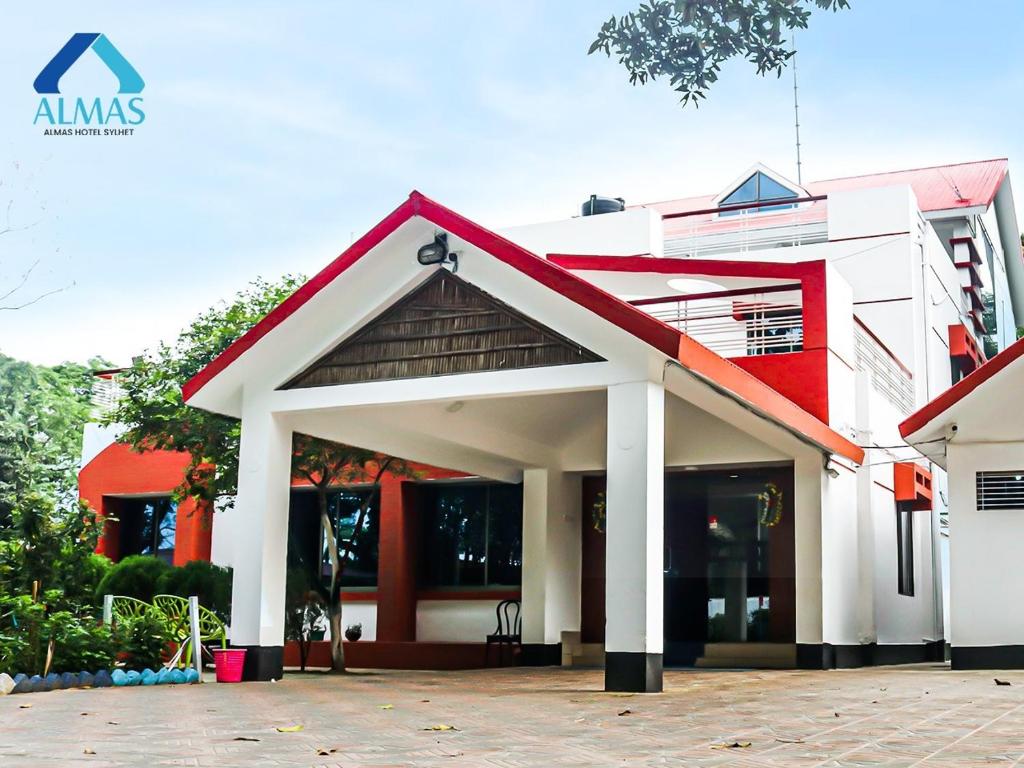 Almas Hotel Sylhet في Debpur: مبنى ابيض واحمر بسقف احمر