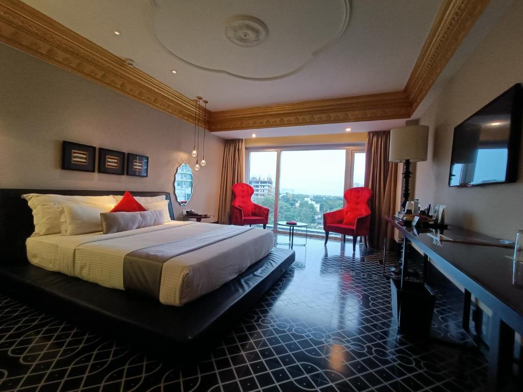 a hotel room with a bed and two red chairs at Boulevard by Design Hotel Chennai in Chennai