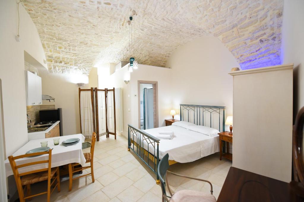 ein Schlafzimmer mit einem Bett und einem Tisch sowie eine Küche in der Unterkunft Casa Masaniello in Martina Franca