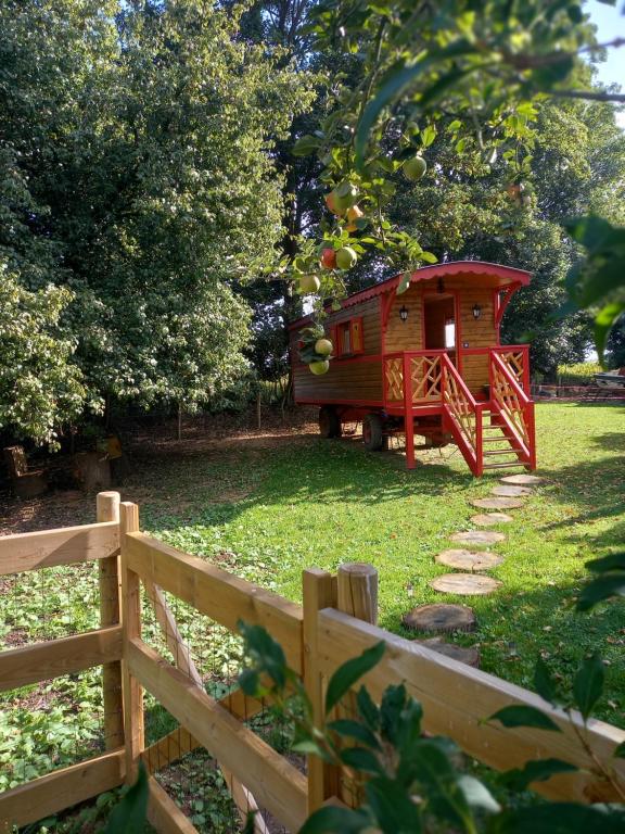 una casetta rossa in un cortile vicino a una recinzione di Les Insolites de Nini a Grainville-Ymauville