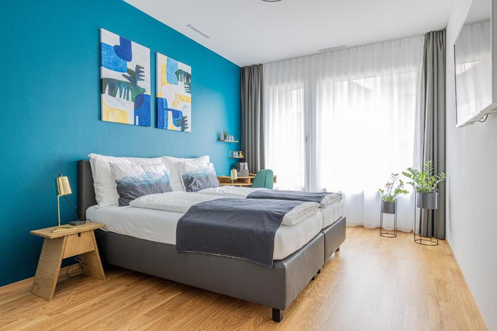 a blue bedroom with a bed and a blue wall at Ambrosia Guesthouse in Rheinfelden