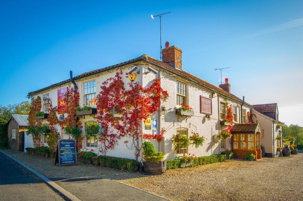 a white building with flowers on the side of it at The King William IV Country Inn & Restaurant in Sedgeford