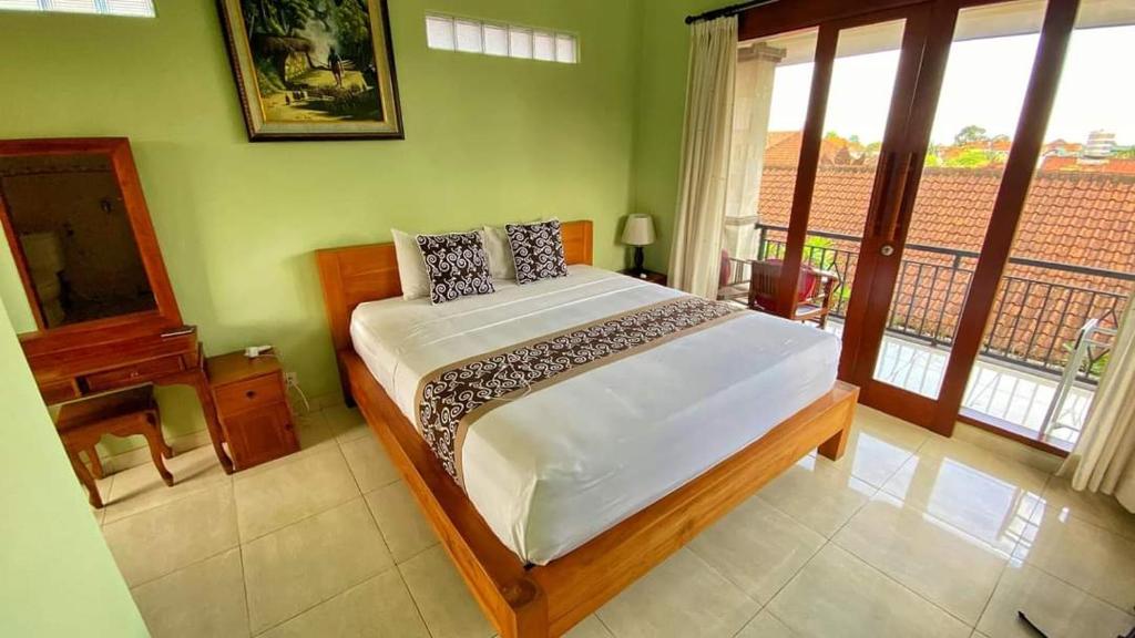 a bedroom with a bed in a room with windows at Sudiana House in Ubud