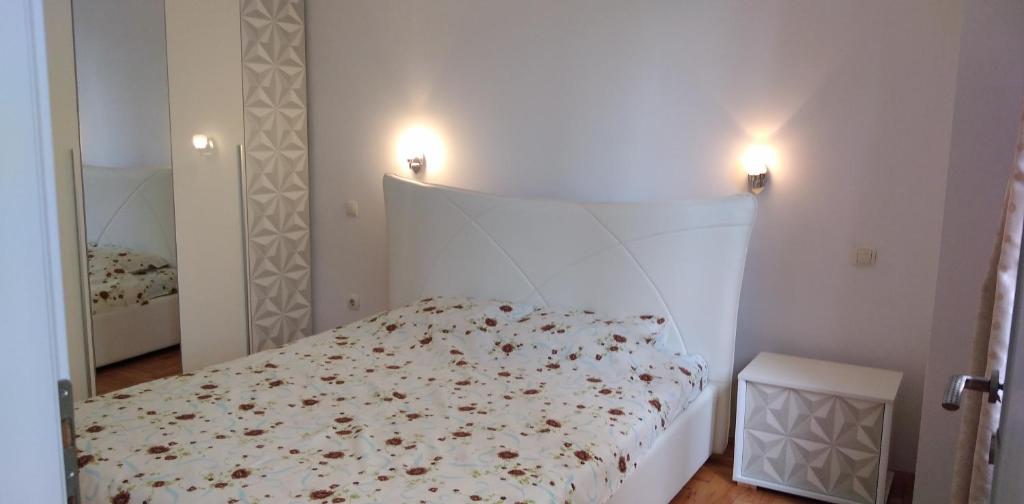 a bedroom with a white bed with flowers on it at Lovely condo next to salt room, bus station in Skopje