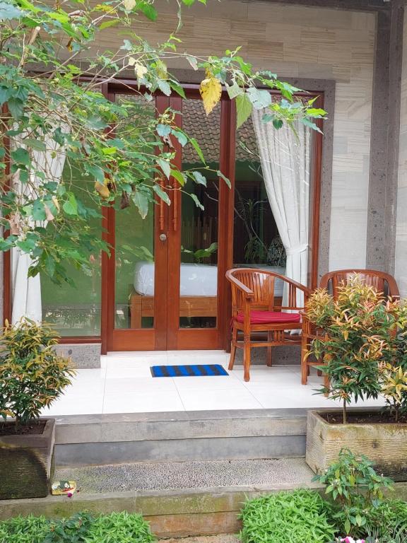 a porch with two chairs and a table at Sudiana House in Ubud
