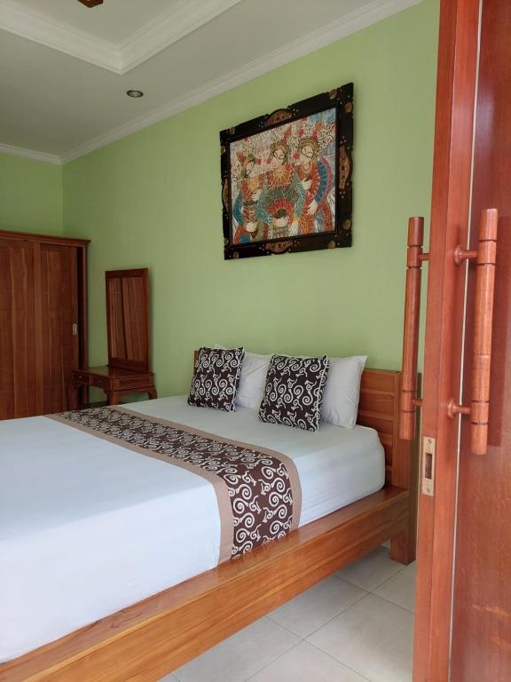 a bedroom with a bed and a painting on the wall at Sudiana House in Ubud