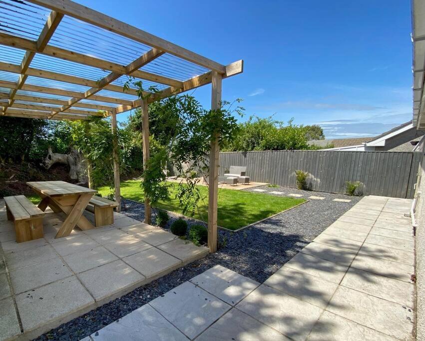 a patio with a picnic table and a wooden pergola at Cosy bungalow in countryside village near coast in Pembroke