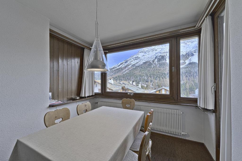 a dining room with a table and a view of a mountain at Chesa Arlas - St. Moritz in St. Moritz