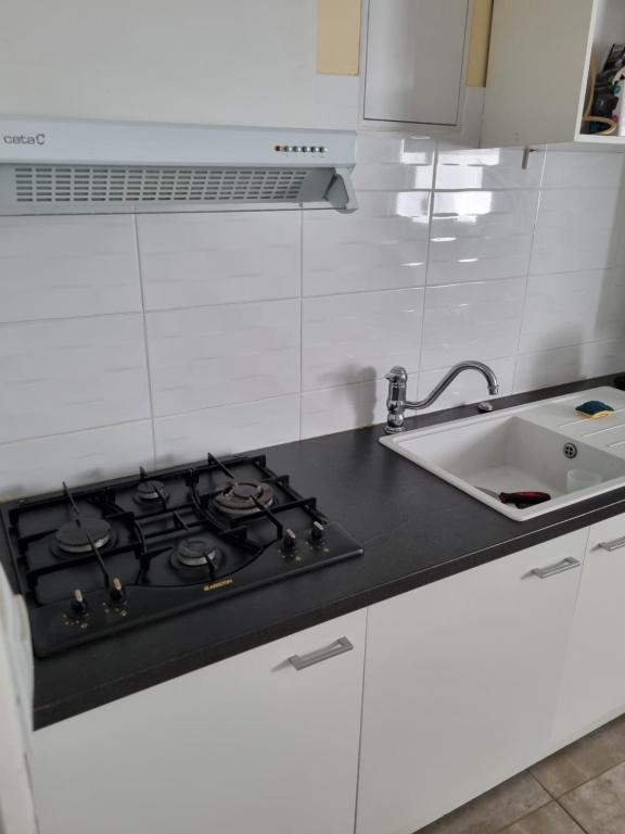 a white kitchen with a stove and a sink at T1 meublé in Saint-Chamond