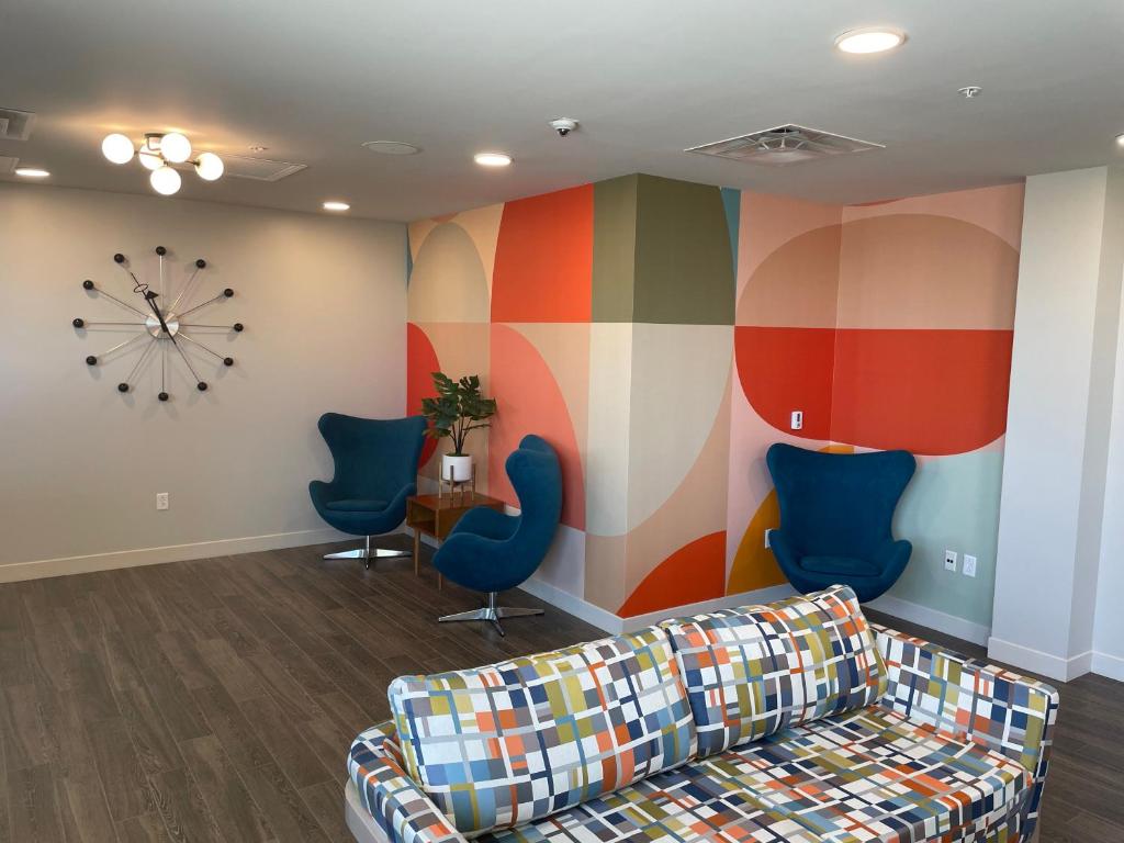 a waiting room with a couch and chairs and a clock at The Orbit Hotel, Trademark Collection by Wyndham in Fairview Park