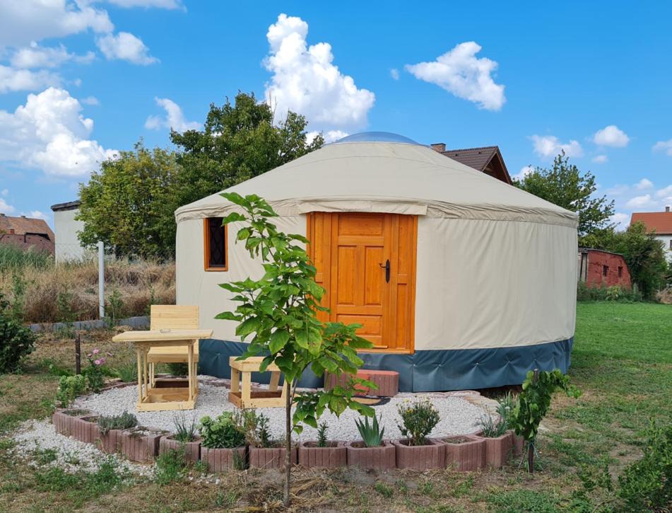 a yurt with a wooden door in a yard at Jurtafarm Ráckeve - a nomád luxus in Ráckeve