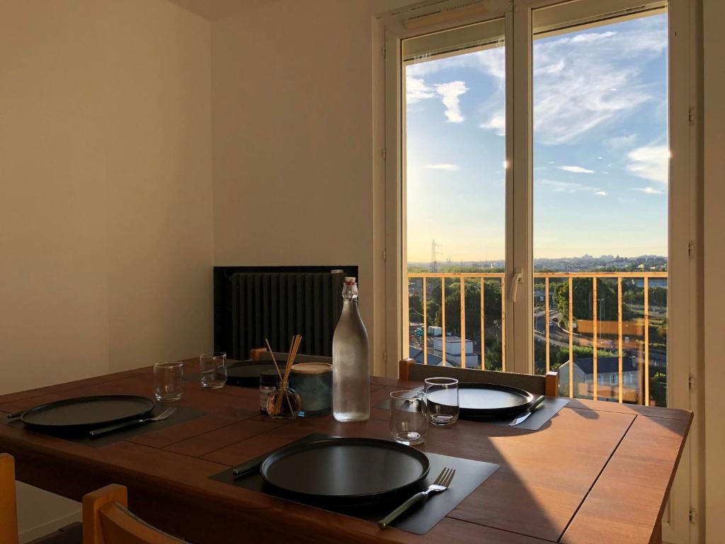 a table with a bottle on top of it with a window at LE PERSICOPE Appart complet, 2 chambres à 5 min du centre ville in Mondeville