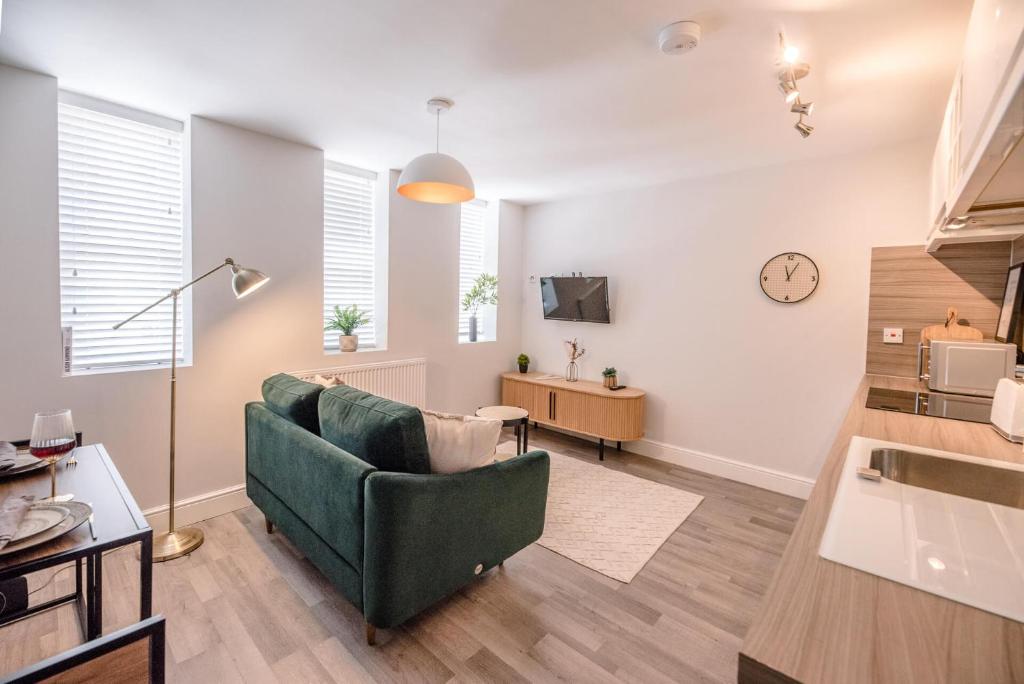 a living room with a couch and a clock on the wall at Guildhall Street Apartment in Bury Saint Edmunds