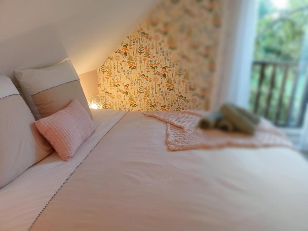 1 dormitorio con 1 cama con sábanas blancas y almohadas rosas en Les chambres du Vert Galant Le lever du soleil en Verlinghem