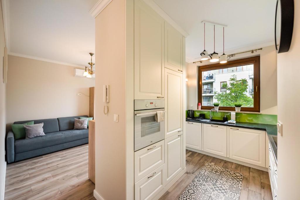 a kitchen with white cabinets and a blue couch at Prestige Verdant Apartment in Warsaw