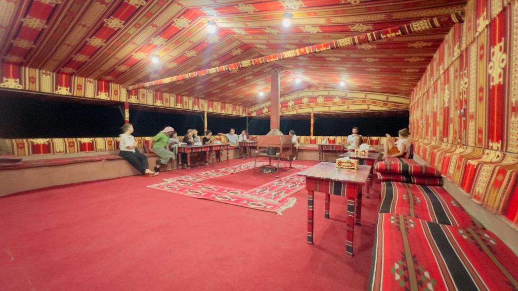 een grote kamer met mensen die aan tafels zitten bij Bedouin host camp& with tour in Wadi Rum