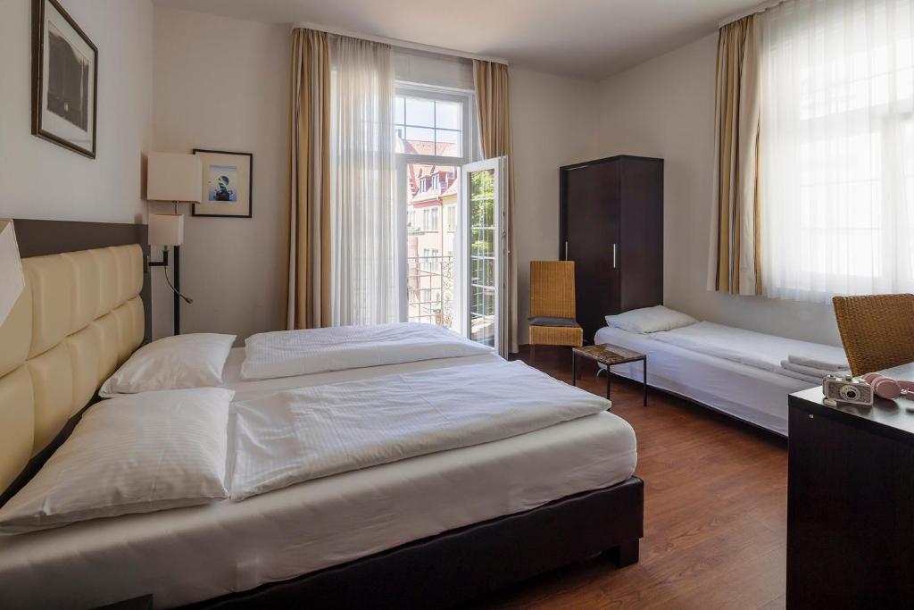 - une chambre avec un grand lit et une fenêtre dans l'établissement Hotel Minerva, à Fribourg-en-Brisgau