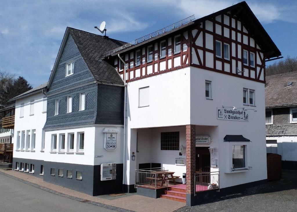 un gran edificio blanco con techo negro en Landgasthof Steuber en Bromskirchen