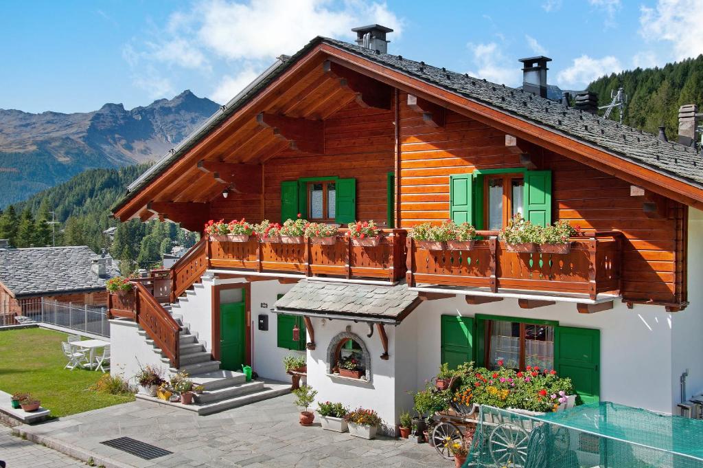 una casa in montagna con fiori sul balcone di Ginepro Casa Vacanze a Madesimo