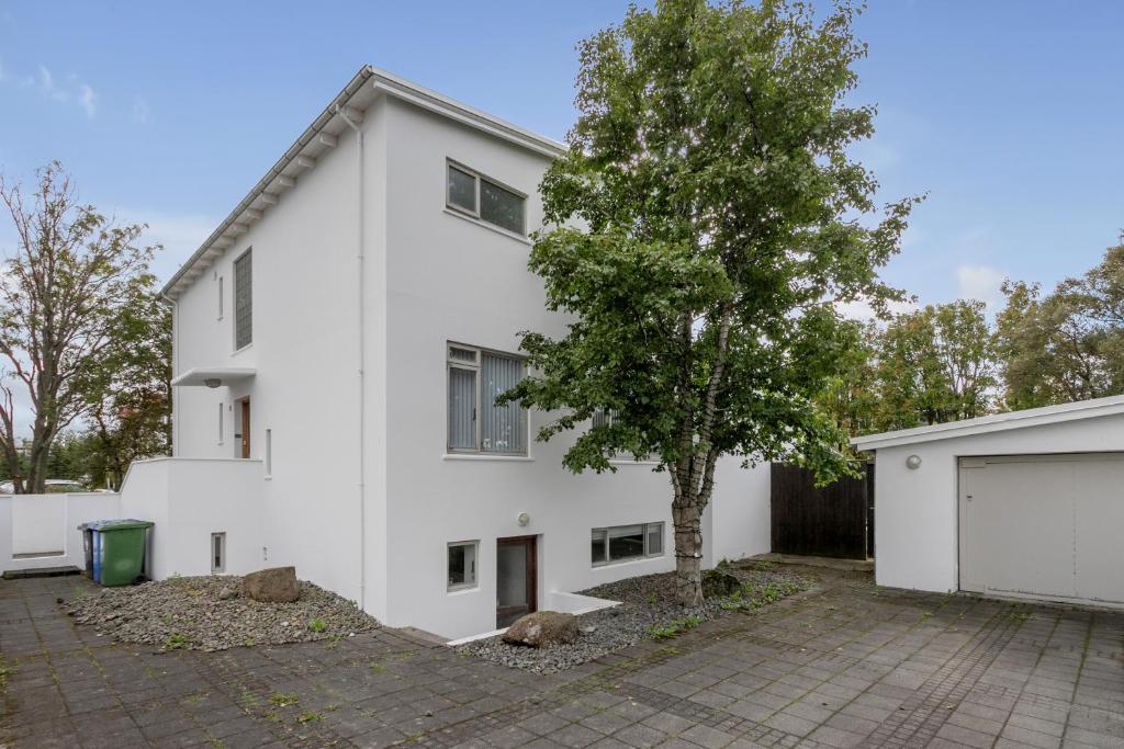 Una casa blanca con un árbol delante. en Luxurious Private Villa, en Reikiavik