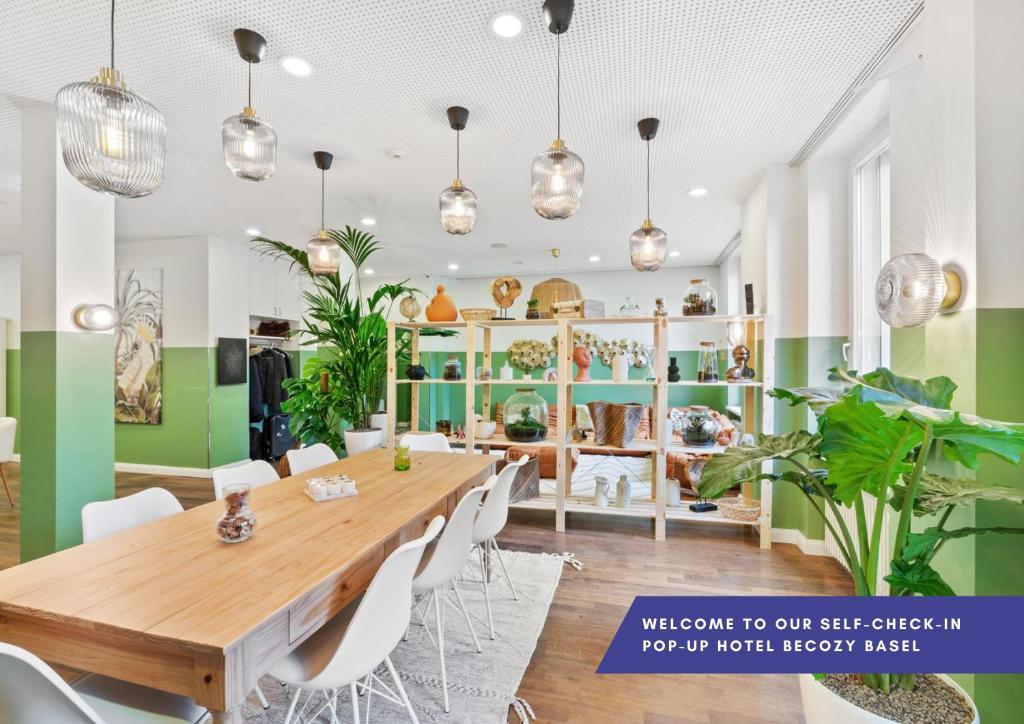 une salle à manger avec une table en bois et des chaises blanches dans l'établissement Becozy Self Check-in Hotel Basel an der Messe, à Bâle