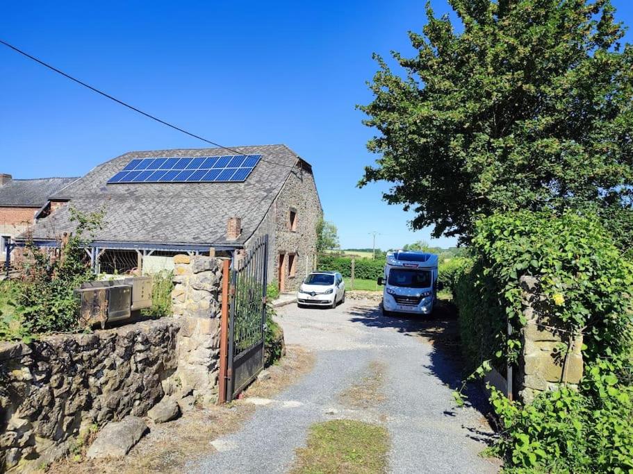 une voiture et un bus garés sur une route à côté d'une grange dans l'établissement LE CHAMPS DES LIEVRES, à Beaumont