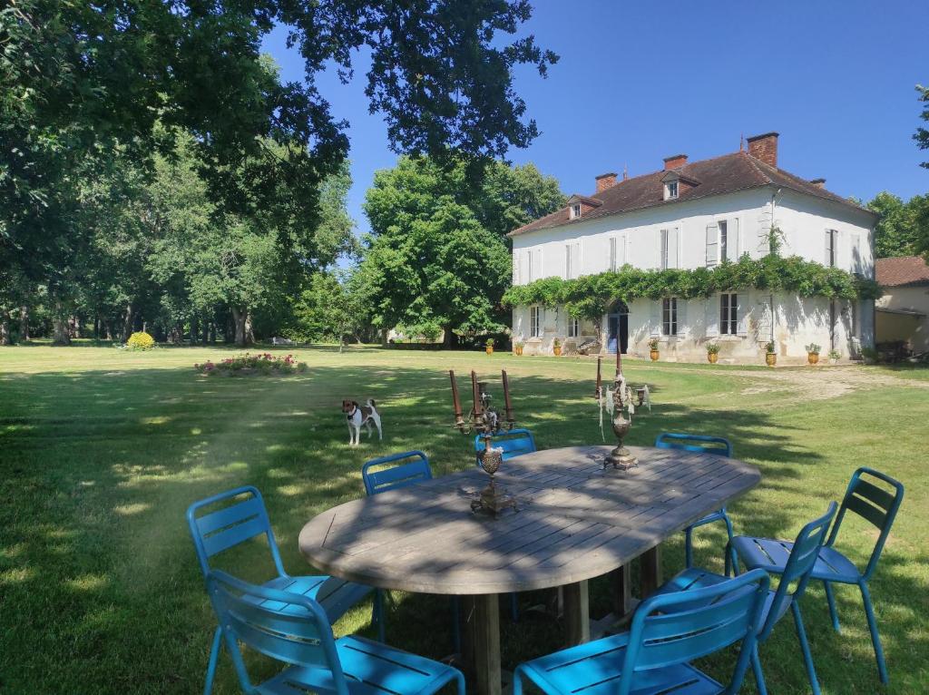 a table with blue chairs in front of a house at Domaine de Cremens 