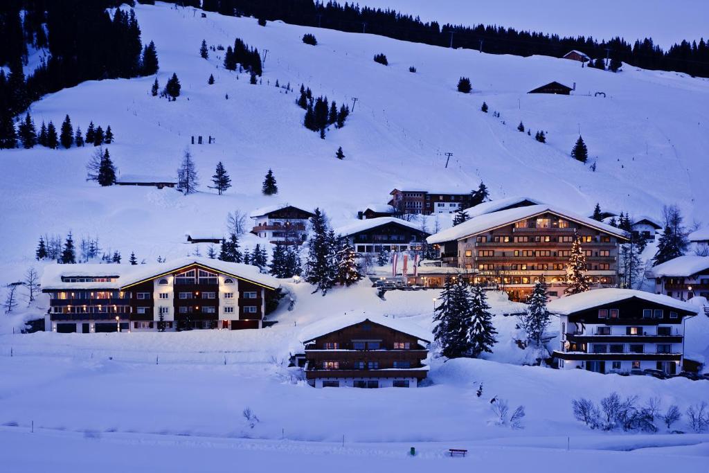 un groupe de bâtiments sur une montagne enneigée dans l'établissement Hotel Plattenhof, à Lech am Arlberg