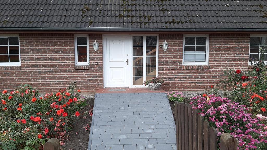 een stenen huis met een witte deur en wat bloemen bij Ferienwohnung Langfeld in Kronsgaard