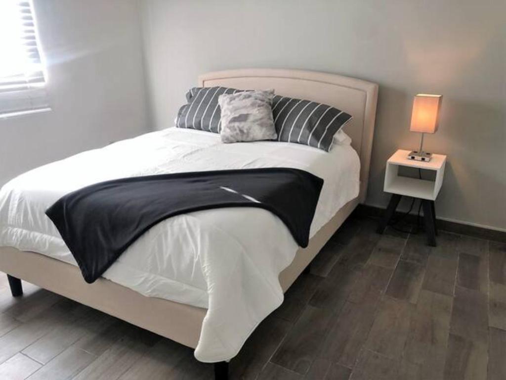 a bedroom with a large white bed with a side table at Lovely 1 Bedroom Apartment w/private Parking in Ensenada