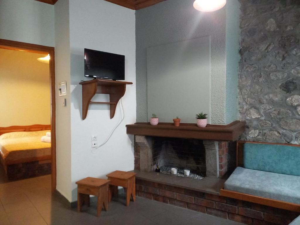 a living room with a fireplace with a television and a bed at Potamolithos Suites in Konitsa