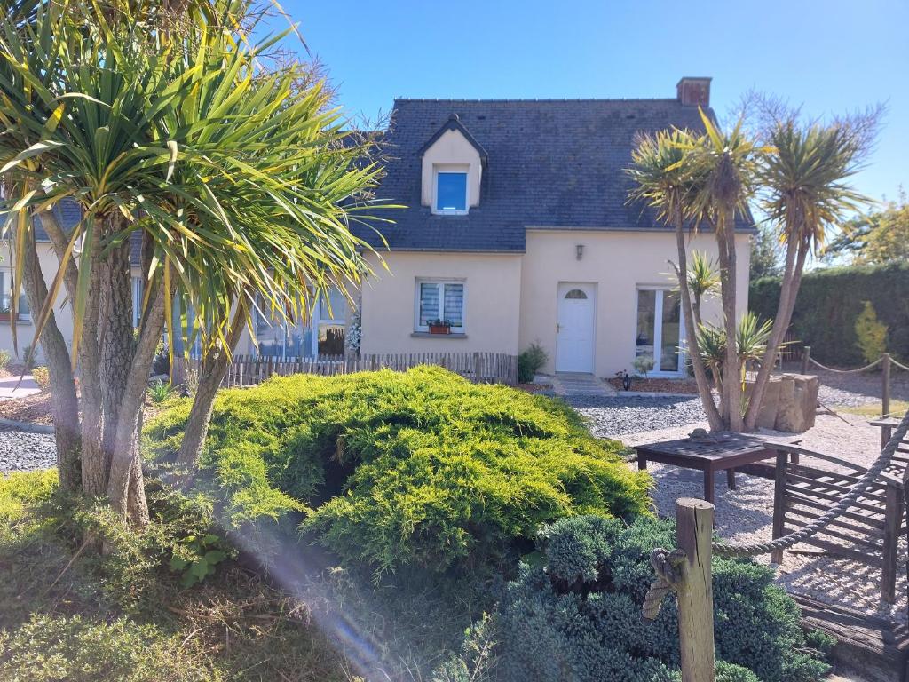 a house with palm trees and a bench in front of it at Chambres d&#39;hôtes chez l&#39;habitant - Bed&amp; Breakfast homestay in Huisnes-sur-Mer