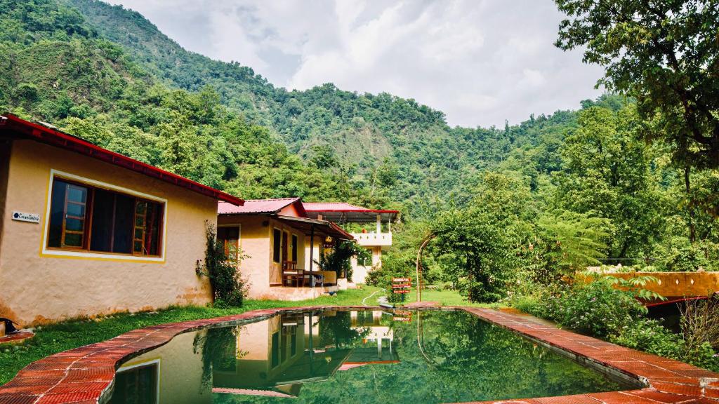 a house with a swimming pool in front of a mountain at Shiv Shakti Yogpeeth Cottages in Rishīkesh