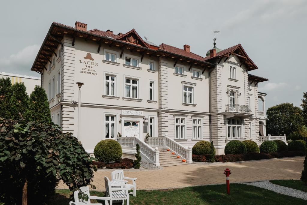 un gran edificio blanco con 2 sillas blancas delante en Pałac Lacon en Kazimierza Wielka