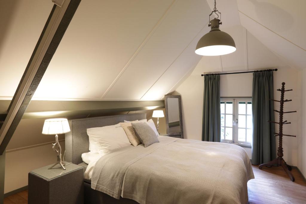 a bedroom with a large white bed and a lamp at Lindenhof & Guesthouse in Garderen