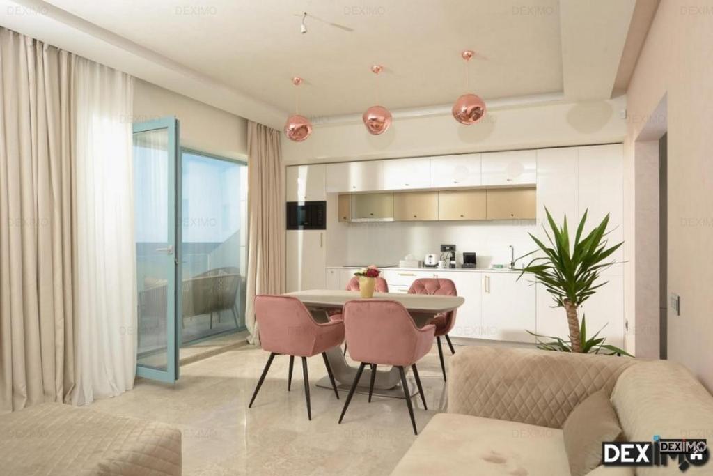 APARTAMENT De LUX ZEV MEDITERANEO في مامايا نورد نافورداي: غرفة معيشة مع طاولة وكراسي ومطبخ