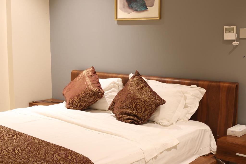 a bed with brown and white pillows on it at Rahhal Hotel Suites in Yanbu