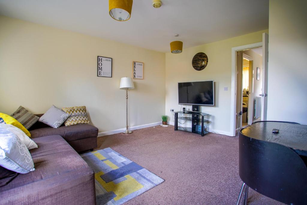 a living room with a couch and a flat screen tv at Chattel Coventry - Massive Homely space with Garden, dedicated Office space & Free Parking in Longford