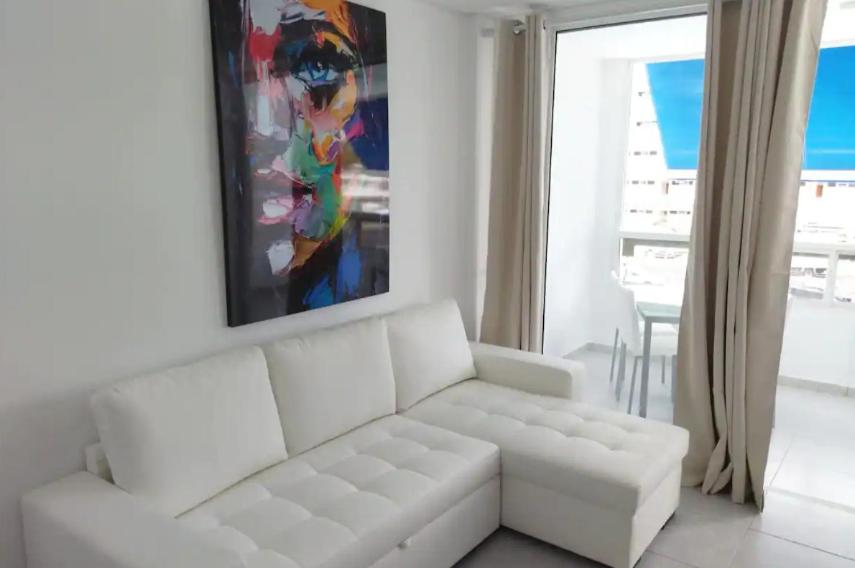 un soggiorno bianco con un divano bianco e un dipinto di Playa del Inglés 5 min walk from Yumbo! 304 a Maspalomas
