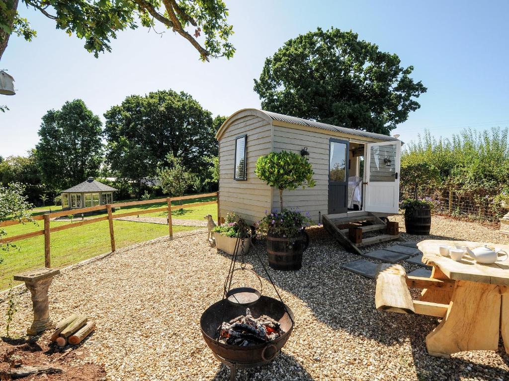 a tiny caravan in a garden with a table and a grill at Orchard Retreat in Crediton